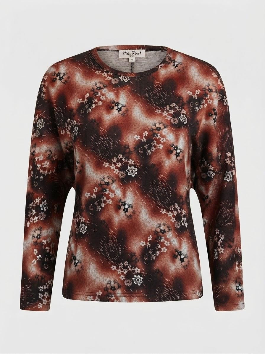 A long-sleeve crewneck top by Miss Pacific, featuring an abstract smoky brown and black pattern overlaid with small white floral motifs, shown against a light gray background.